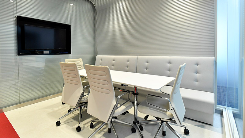 ソファ席とモニターを備えた白を基調とした会議室